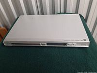 Top-front view of the Philips DVP 3960/37 DVD player showing a slim silver design with disc tray and control buttons in front.