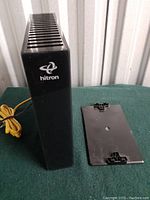 Hitron CDA3-20 Gigabit Cable Modem standing vertically with power cord wrapped and black base stand separated beside it.