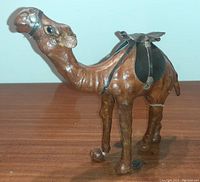 Side and front views of a brown leather camel figurine with saddle, showing details and condition including a small crack on the left rear leg.