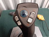 Close-up of the joystick handle showing multiple buttons, including a circular directional control with a transparent cap.