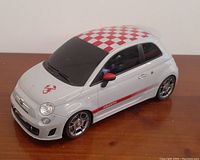 White 1:14 scale Mondo Motors Fiat 500 Abarth model with red checkered roof and red side stripes on a wooden surface