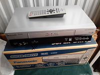 Panasonic Super Drive VHS VCR on original box with remote control on top.