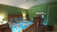 Bedroom with assembled IKEA Verdal pine wood queen bed frame with colorful bedding and two nightstands.