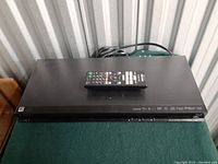 Top view of the Sony Blu-ray/DVD player with the remote control placed on top, showing a clean, matte black surface.