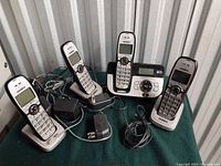 Photo showing the main base unit with digital answering system and four cordless handsets with their charging docks on a green cloth surface.