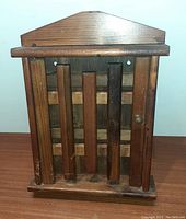 Front view of the wall mounted wooden key box showing vertical wooden slats and knob.