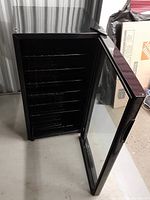 Open front view of Danby wine cooler showing empty wire shelves inside and glass door opened.