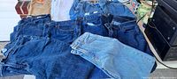Photo showing 10 pairs of women's jeans and pants laid out on a surface in various colors including denim blue, tan and white.