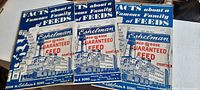 Three Eshelman Red Rose Guaranteed Feed catalogs displayed together, showing front covers with blue and white historic feed mill building illustration and animal icons on the left side. Catalogs are identical in design with slight variations in color intensity.