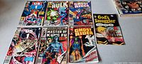 Photo showing full lot of 7 comic books laid out on a surface, visible front covers of each comic and booklet.