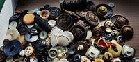 Wide view of assorted antique buttons showing a variety of materials and designs including military and bakelite styles.