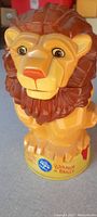 Close-up image of plastic lion-shaped mug with circus branding on base, showing lion face and mane details.