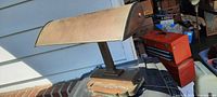 Side view of heavy vintage desk lamp on porch showing brass-tone curved shade and ornate base.