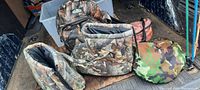 Image showing camouflage padded boots covers, equipment bags and insulated carry bags on a floor surface