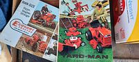 Photo showing the Yard-Man brochure cover with colorful images of red riding mowers and lawn equipment affecting the yard with two men operating the equipment.