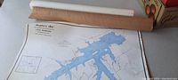Angler's Atlas Lake Marburg marine map partially unrolled on a flat surface with cardboard tubes seen in background.