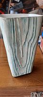 Front angled view showing textured vertical lines and blue highlights on vase