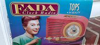 Front side of original box showing vintage styled woman pointing at FADA clock radio image and branding text