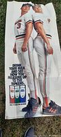 Full length view of the vintage Baltimore Orioles paper measure poster showing two players in uniform back-to-back, with visible fold lines and milk advertisement at the bottom.