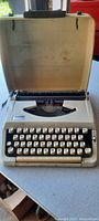 Open vintage portable typewriter showing cream body, black keys and brand "Wizard" on front.