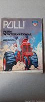 Front cover of the 1977 Penn Winternational tractor pull program featuring an illustrated red tractor under smoke and clouds.
