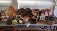 Wide shot showing arrangement of multiple wicker baskets, small decorative items and photo albums on a table