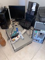 Desktop computers and accessories including monitor, speakers, cords, and power strip arranged on the floor
