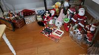 Wide shot of the holiday ornaments and decor arranged on the floor including Santa and snowman figurines, Mickey Mouse ornament, decorative boxes and baskets.