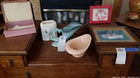 Overview of six items displayed on a wood table including Hull pottery pieces and framed art items.