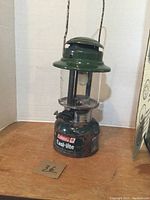 Full view of the Coleman green Easi-lite lantern showing the overall condition and cracked glass globe.