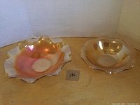 Both marigold pattern depression glass bowls displayed side by side showing size difference and iridescent finish.
