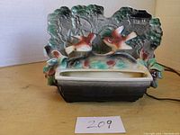 Front view of the ceramic planter television light featuring two detailed birds and a scenic background relief.