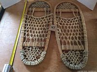Pair of wooden Bearclaw snowshoes side by side on wooden surface with measuring tape showing 26 inches length