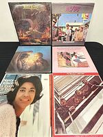 Top view of six vinyl LP album covers including Judas Priest, AC/DC, Moody Blues, Nancy Wilson, and The Beatles 1962-1966 Double Red Album