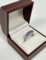 Ring displayed in burgundy presentation box with white satin interior.
