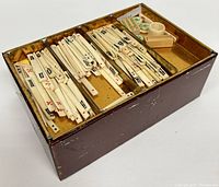 Mah-jong tiles organized in four compartments inside the open box.