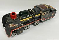 Side and front angle view of the black tin lithographed toy train engine marked GIANT with a red smokestack and jockey on horse artwork on the front.