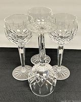 Four Waterford crystal wine hock goblets arranged with three upright and one lying on its side, showing detailed diamond cut pattern and starburst base.