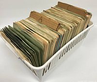 Wide view of white plastic bin filled with over 50 45 RPM vinyl records organized with cardboard dividers labeled A, B, C, D