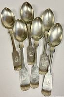 Set of six sterling silver teaspoons arranged with monogram 'D' visible on handles