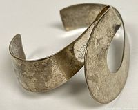 View of flowing modernist sterling silver Birks cuff bracelet showing open-ended bangle design with smooth curves and matte surface.