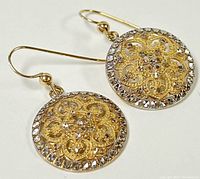 Two-tone filigree earrings on white background, close-up of decorative discs