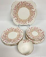View of luncheon plates, dessert plates, saucers, sugar bowl, and cake plate with floral and gold pattern.
