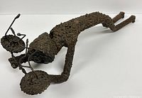 Front angled view of the handmade cast metal bicycle rider statue with textured bronze finish.