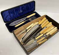 Assortment of 20+ cutlery pieces with cream celluloid handles and sterling silver bands, some forks and knives, displayed together.