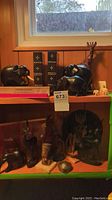 Shelf with multiple wooden animal figurines including elephants, giraffe, and antelope, plus two wooden elephant bookends and a small white figurine