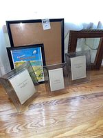 Six picture frames displayed on hardwood floor: three Waterford Crystal frames with ribbed detailing in front; various wood frames behind.