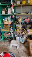 Shelves filled with assorted hardware, tools, and supplies including wire coils, ropes, paint tools, bags of compound, and assorted boxes.
