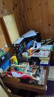 Photo showing printer, cartridges, envelopes, paper, various office supplies spread on a wooden table.