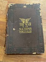 Front cover of the portfolio showing the title 'The War of the Nations Portfolio' in gold lettering on a black worn cover with an eagle design.